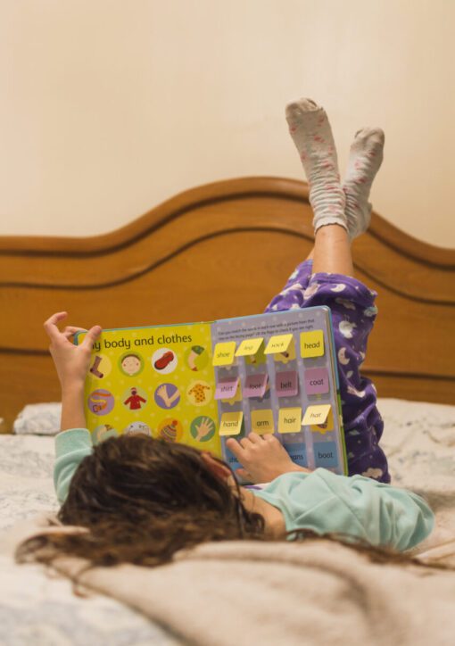 Criança deitada na cama explorando livros sensoriais