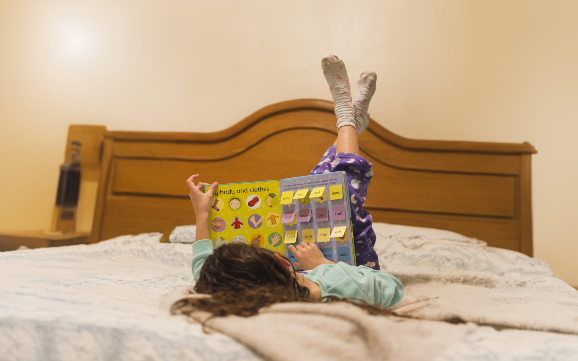 Criança deitada na cama explorando livros sensoriais